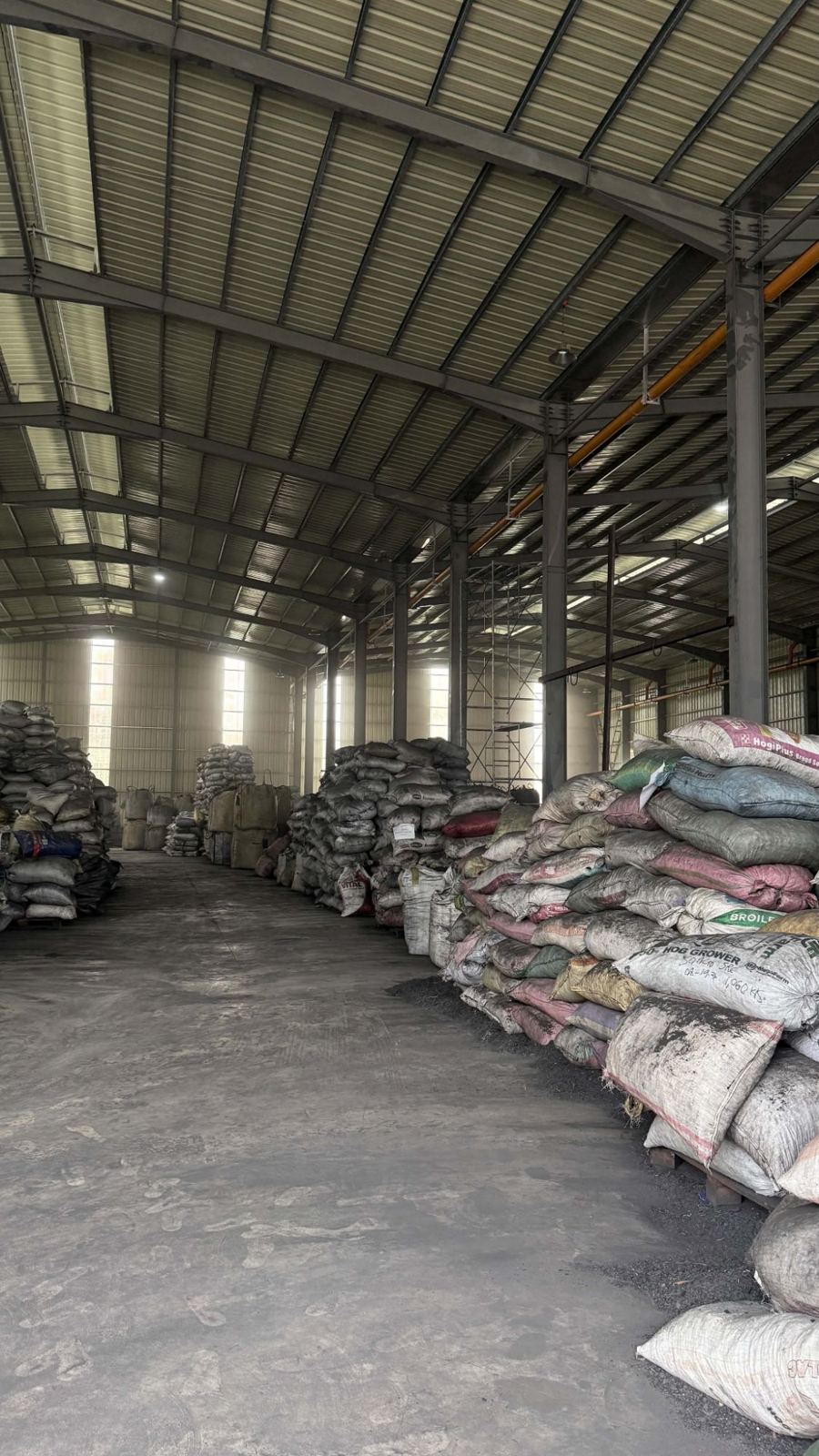 Rows of coconut shell charcoal sacks stacked inside a warehouse