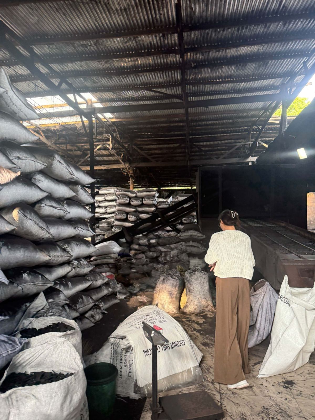 Sacks of coconut shell charcoal beside a platform weighing scale